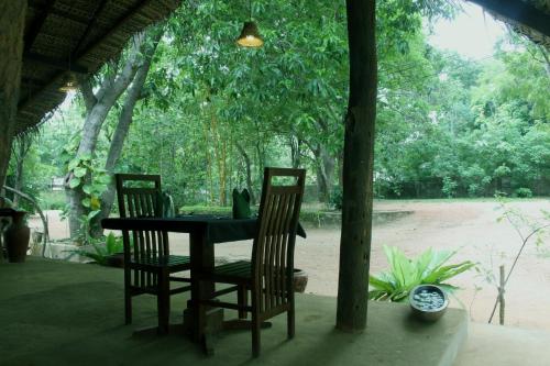 a table and two chairs with a table and trees at A4 Villa & Spa. in Habarana