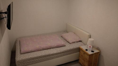 a small bed with a pink blanket and a night stand at Landhotel Alte Mühle in Modautal