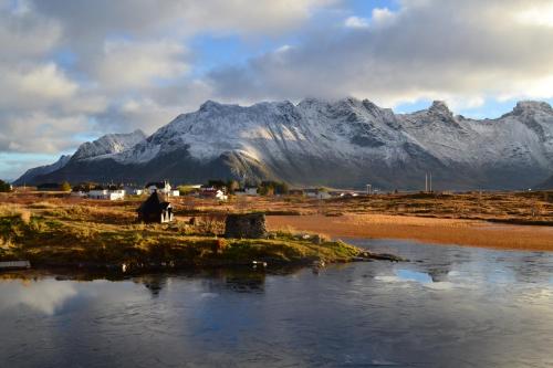 a mountain range in the distance with a village and a river at Milas House two apartments in Fredvang