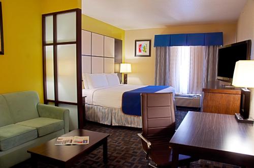 a hotel room with a bed and a couch at Super 8 by Wyndham Irving/DFW Apt/North in Irving
