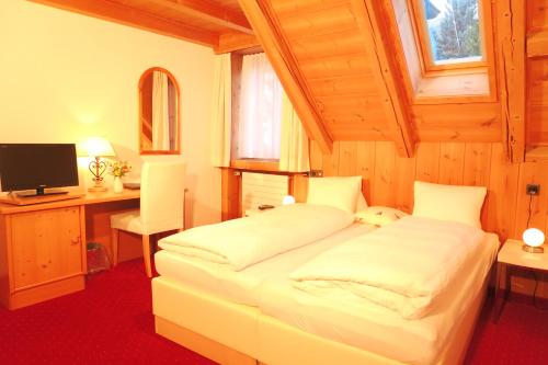 a bedroom with a bed and a desk and a television at Hotel Restaurant GABRIEL in Scuol