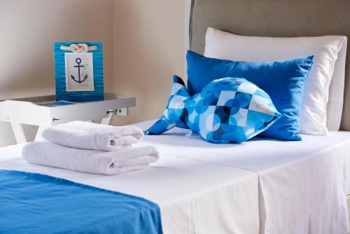 a bed with blue and white pillows and towels on it at Elaia Luxury Suites Lagonisi in Lagonissi