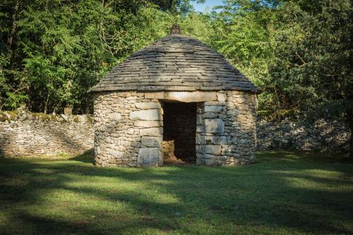a stone shelter in the grass in a field at Hôtel Le Troubadour à Rocamadour in Rocamadour