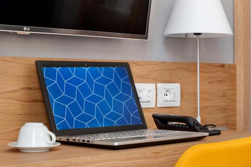 a laptop computer sitting on a desk with a phone at Hotel Medinblu in Reggio Calabria