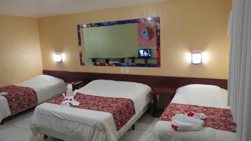 a hotel room with two beds and a mirror at Beira Mar Porto de Galinhas Hotel in Porto De Galinhas