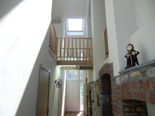 a hallway with a staircase and a clock on a wall at B&B Au Coeur de Villers in Villers-Sainte-Gertrude