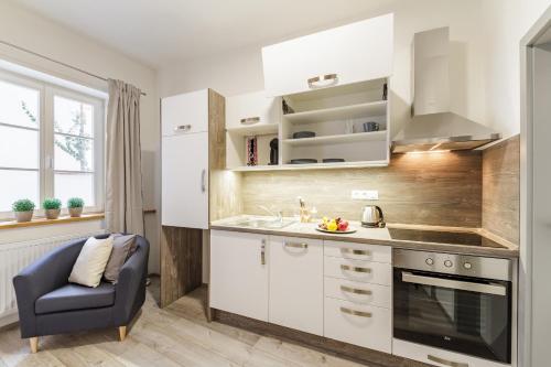 a kitchen with white cabinets and a blue chair at Downtown Royal Apartments in České Budějovice