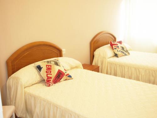 El Apartamento de María في لوغو: غرفة نوم بسريرين مع شراشف بيضاء