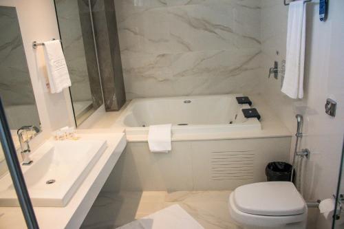 a bathroom with a tub and a toilet and a sink at Ity Hotel in Cristalina