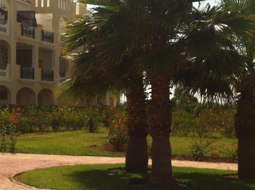 two palm trees in a park in front of a building at Oriental Dary in Saidia 