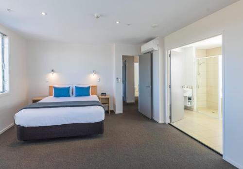 a bedroom with a large bed with blue pillows at Quest Cathedral Junction Serviced Apartments in Christchurch