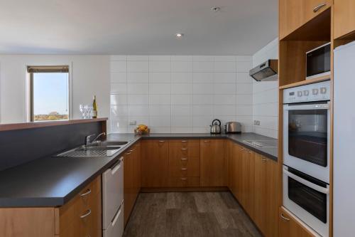 a kitchen with a sink and a stove top oven at Quest Cathedral Junction Serviced Apartments in Christchurch