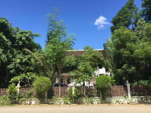 a fence in front of a house with trees at Ban Vivanh chambres d'hotes in Luang Prabang