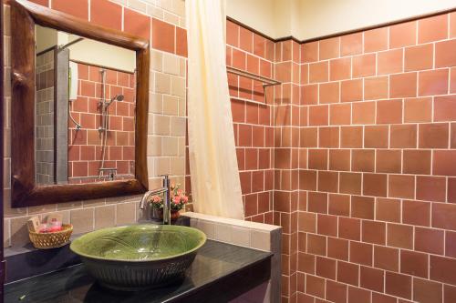 ein Badezimmer mit einem grünen Waschbecken und einem Spiegel in der Unterkunft Oh Amphawa Boutique Resort in Amphawa
