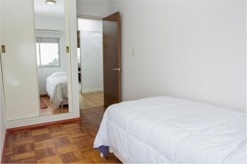 1 dormitorio con cama blanca y espejo en Ginkgo Port Colonia, en Colonia del Sacramento