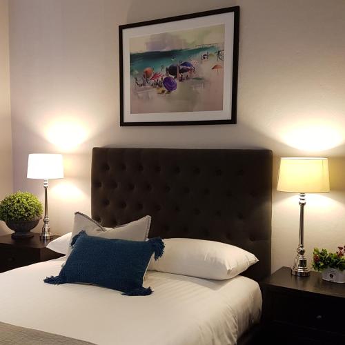 a bedroom with a bed with a blue pillow and two lamps at Northern Star Hotel in Hamilton