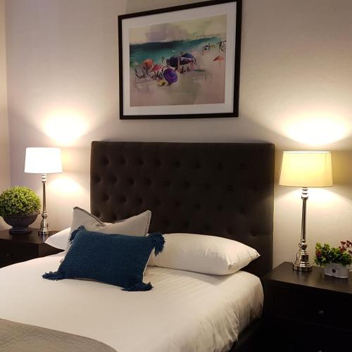 a bedroom with a bed with a blue pillow and two lamps at Northern Star Hotel in Hamilton
