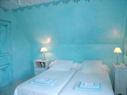 a blue bedroom with two beds with towels on them at Maison d'Hôtes Le Moulin Pointu in Sainte-Nathalène