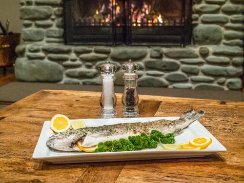 a fish on a plate on a table with lemon slices at Isolation Bay in Lake Tekapo