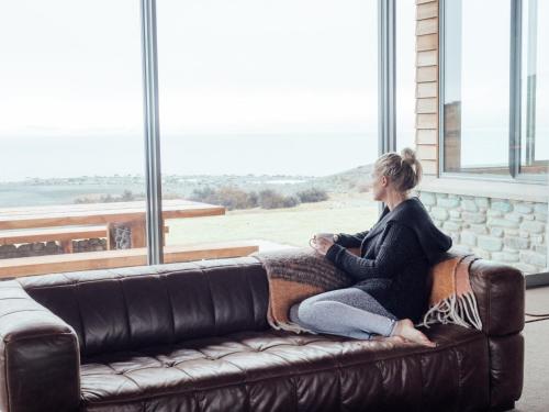 a woman sitting on a couch looking out a window at Isolation Bay in Lake Tekapo