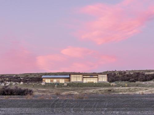 a building in a field with a pink sky at Isolation Bay in Lake Tekapo