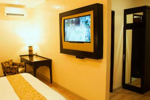 a room with a bed and a television on a wall at Palm Grass Hotel in Cebu City