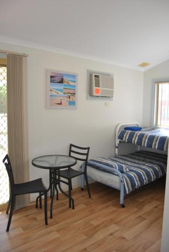 a bedroom with a bed and a table and chairs at Port Gregory Caravan Park in Gregory