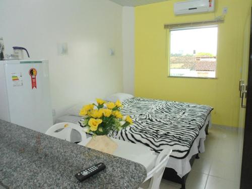 una habitación con una mesa con un jarrón de flores amarillas en Residencial Dom Fernando, en Belém