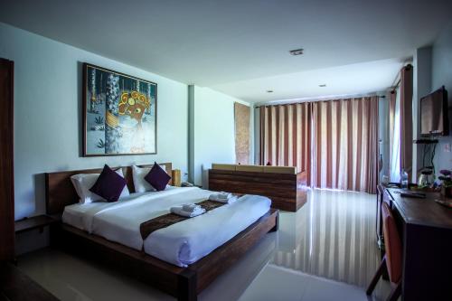 a bedroom with a large bed and a desk in it at Tamali Hotel in Nakhon Si Thammarat