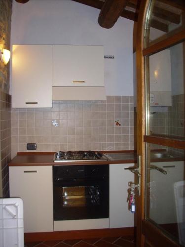 a kitchen with white cabinets and a stove top oven at Casa Valeria in Cinigiano