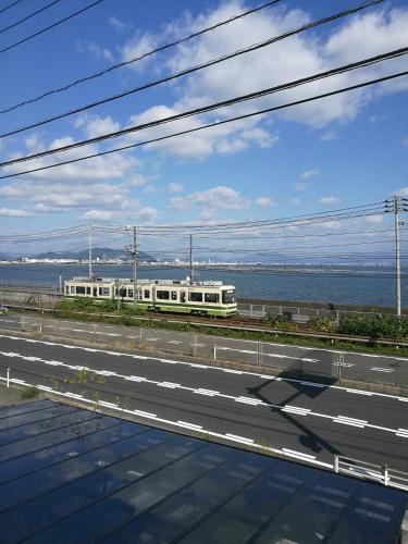 a train on the tracks next to a road at Guest House Diphylleia Grayi in Hatsukaichi