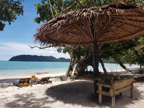 a beach with chairs and an umbrella and the ocean at Vijit Bungalow in Ko Phayam