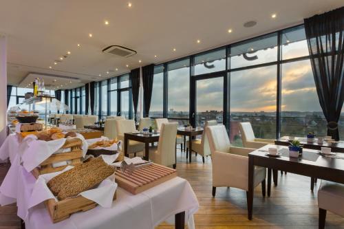 a restaurant with tables and chairs and large windows at Hotel IV Jahreszeiten Lübeck in Lübeck
