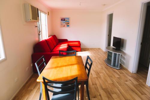 a living room with a table and a red couch at Port Gregory Caravan Park in Gregory