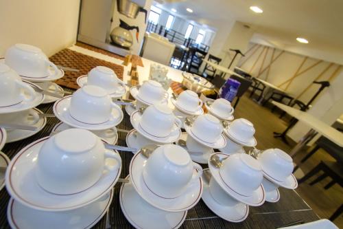 a group of white cups and saucers on a table at Imperial Hotel Express in Kisumu