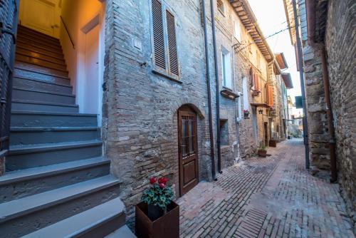 an alley in an old building with a door and flowers at Hotel Assisivm Antica Dimora AD in Assisi