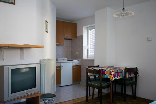 uma cozinha com televisão e uma mesa com cadeiras em Apartment Mavrica em Bovec
