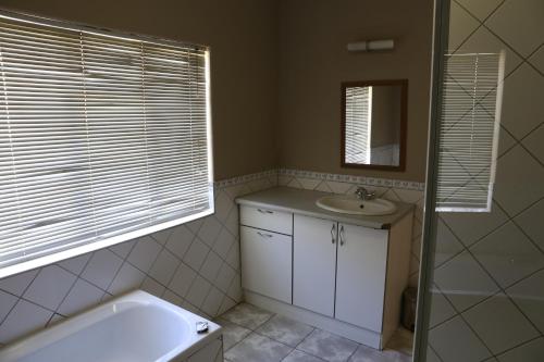 a bathroom with a tub and a sink and a mirror at Klein Windhoek Guesthouse in Windhoek