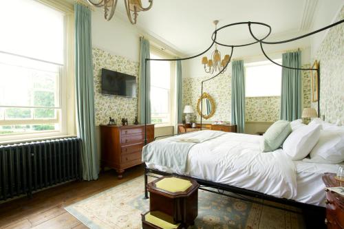 um quarto com uma grande cama branca e janelas em The Crown Hotel em Blandford Forum