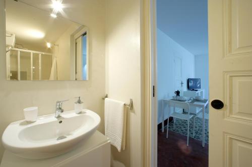 a white bathroom with a sink and a mirror at La Piccola Giudecca in Trapani