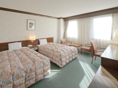 a hotel room with two beds and a table and chairs at New Wel City Miyazaki in Miyazaki
