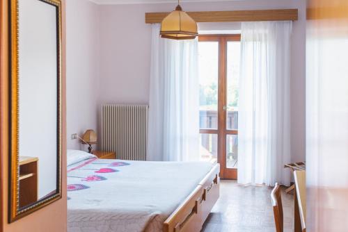 1 dormitorio con 1 cama grande y espejo en Hotel Mignon, en Folgaria