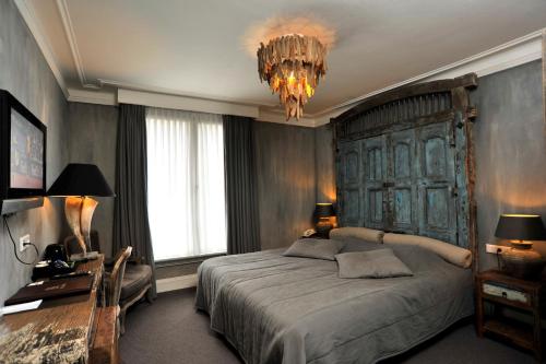 a bedroom with a large bed and a chandelier at Golden Tulip West Ende in Helmond