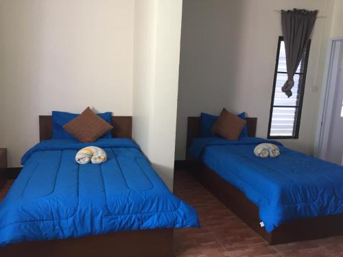two beds in a room with blue sheets at Bansappoori in Lamphun