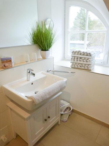a white bathroom with a sink and a window at Heidehüs Seepferdchen in Nebel
