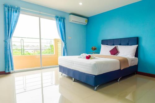 a blue bedroom with a bed and a large window at Jaroonsak Grand in Trang
