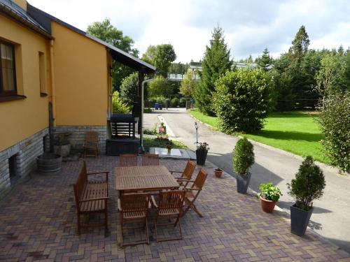 a patio with a wooden table and chairs at Ferienhaus Bergblick - mit Sauna und Dampfbad und Yacuzzi in Sehma