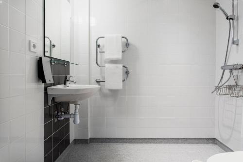 a white bathroom with a sink and a shower at Biz Apartment Solna in Solna