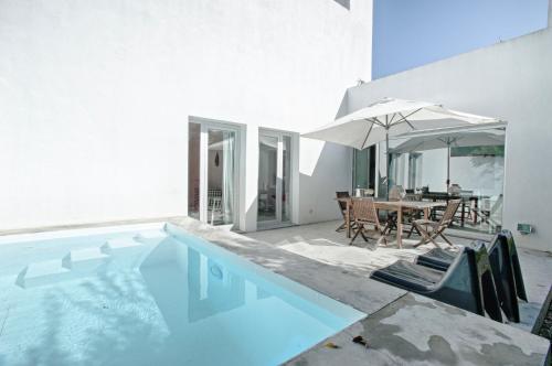 a swimming pool with a table and an umbrella at Melro's Places in Sesimbra