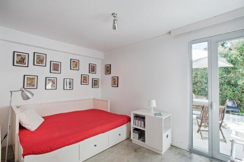 a white bedroom with a red bed and a window at Melro's Places in Sesimbra
